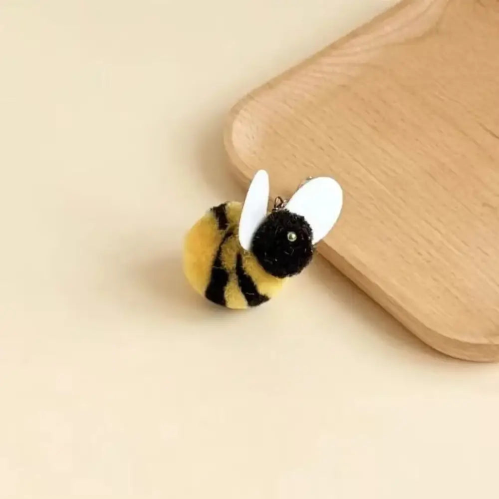 黄と黒の縞模様の胴体と白い翼を備えた、ぬいぐるみの毛むくじゃらのハチの形をしたキーホルダー玩具で、猫おびき寄せ用の玩具として設計されたもの。