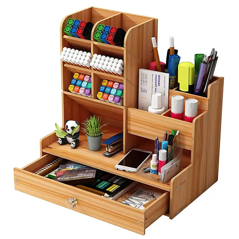 Light brown wooden desk organizer with drawer featuring multiple compartments holding markers pens a phone and small decorative items.