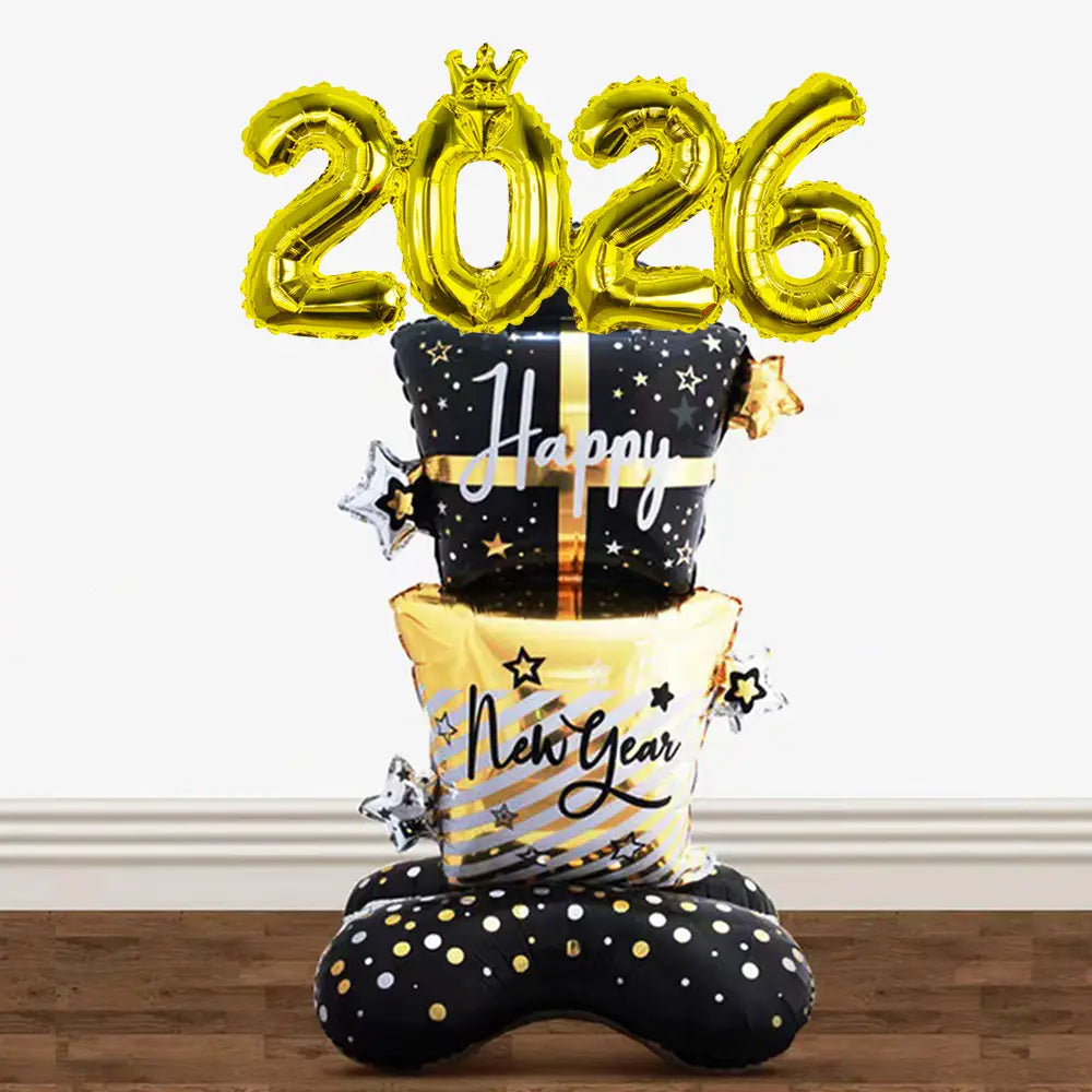 Decoración con globo de Año Nuevo dorado de 2026 que presenta un globo central de lámina de oro con el año 2026 en la parte superior, sobre diseños apilados de cajas de regalo con patrones de estrellas y el texto de feliz año nuevo.
