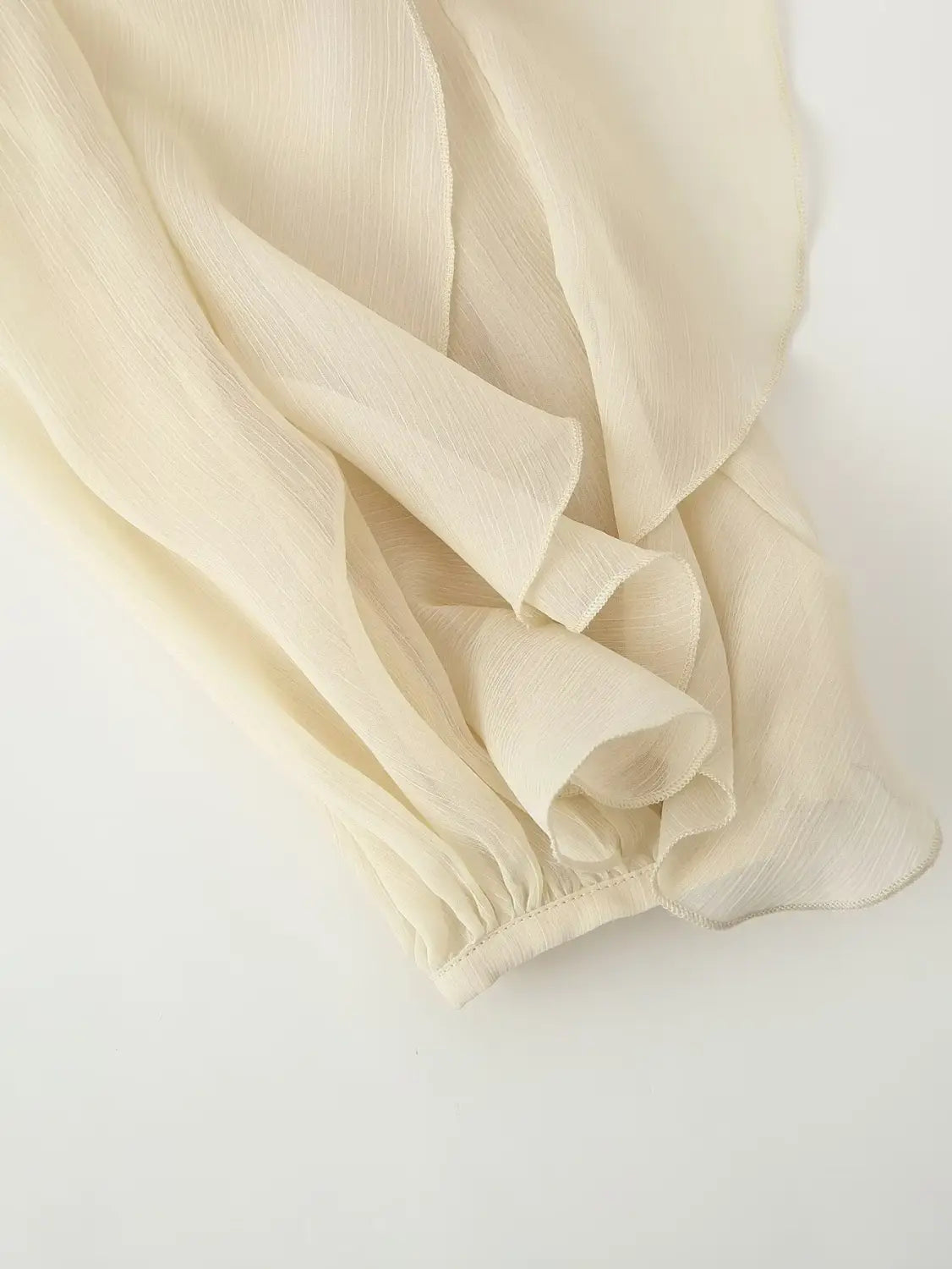 cream-colored chiffon blouse featuring long sleeve ruffle shirt design with delicate ruffled detailing and gathered elastic cuff