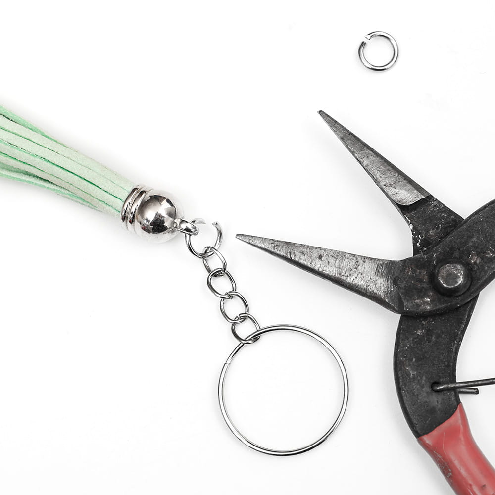 A mint green suede tassel metal keychain with a silver metal ball and split ring chain attachment.
