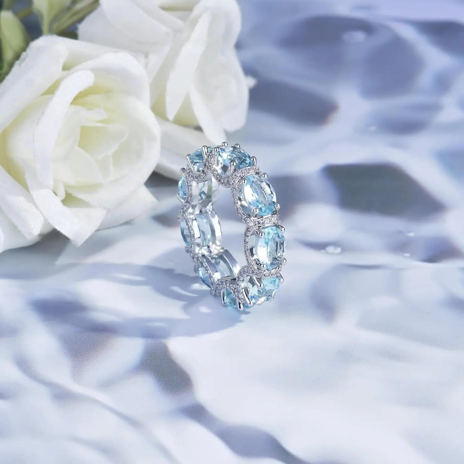 A delicate silver band ring from the Aquamarine Crystal Bridal Jewelry Set adorned with oval-cut sky blue gemstones and smaller sparkling diamonds.