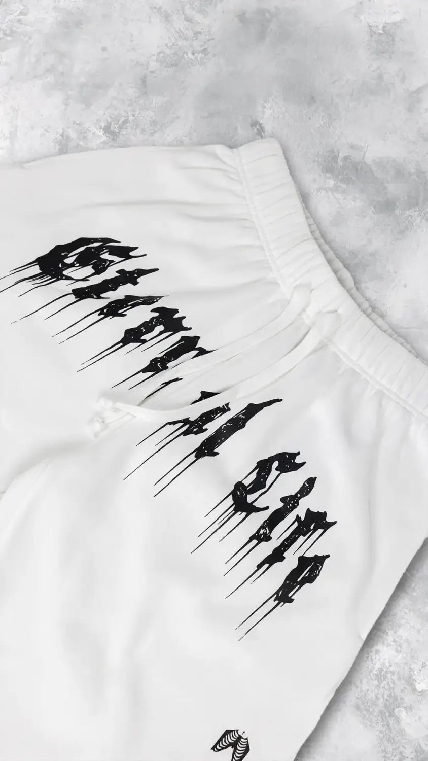 Pantalons d’entraînement graphiques pour hommes, sweatpants blancs, avec des lettres de style graffiti noir et un petit logo sur la partie inférieure de la jambe, adaptés aux vêtements d’entraînement.