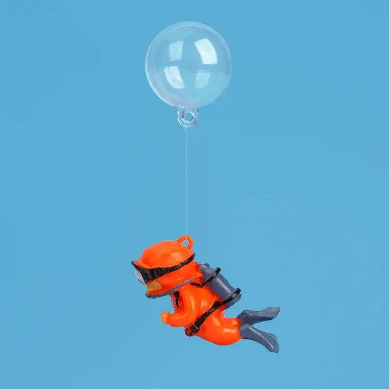 Orange plastic scuba diver figurine with black goggles and gray fins floating upward by a clear balloon for popular aquarium decorations fish tanks landscape decor accessories gifts for aquatic pets.