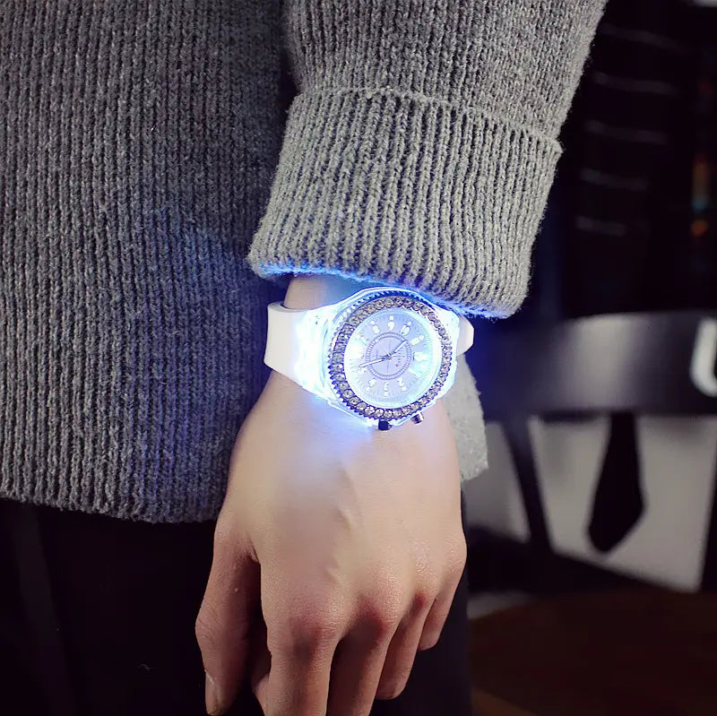 A glowing white led luminous silicone watch with a sparkling rhinestone bezel and silver-toned face worn on a wrist.