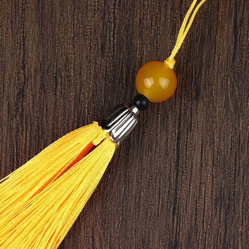 a brass gourd feng shui prosperity ornament featuring a vibrant yellow tassel with a polished amber bead and silver-toned metal cap