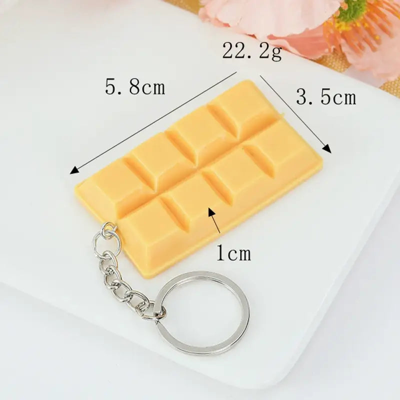 A yellow rectangular chocolate bar-shaped keychain made of metal with a silver chain and ring used as a cartoon chocolate biscuit bag pendant.