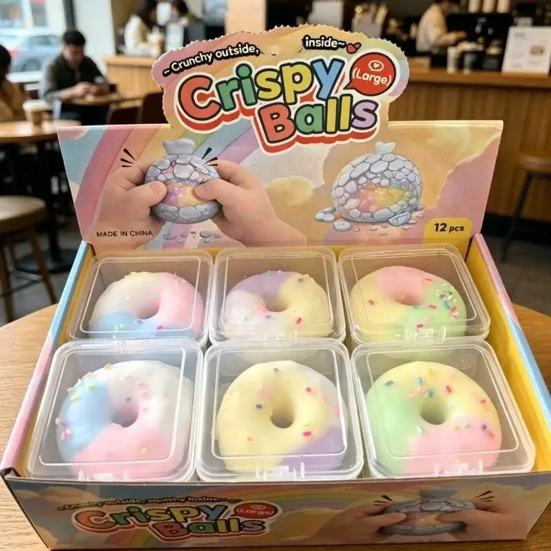jouet antistress d’aspect pastel fabriqué en plastique sans BPA, présentant des billes croustillantes en forme de donuts avec des vermicelles arc-en-ciel et une enveloppe extérieure croquante.