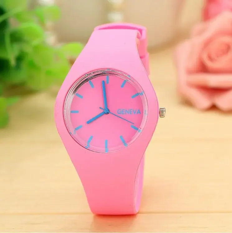 Reloj para mujer de cuarzo de silicio Ginebra con correa de silicona rosa, esfera transparente, manecillas azules y marcadores horarios, y la marca Ginebra en la esfera.