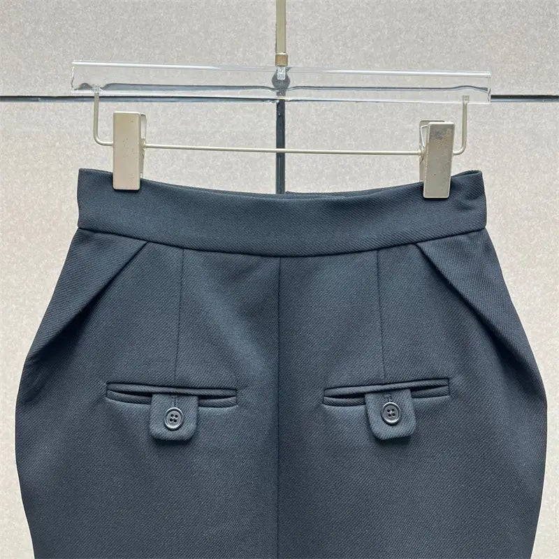 Pantalon tailleur gris foncé, coupe ajustée, avec taille structurée et poches à rabat fermées par des boutons, complétant une jupe crayon grise taille haute de longueur genou au style Y2K.