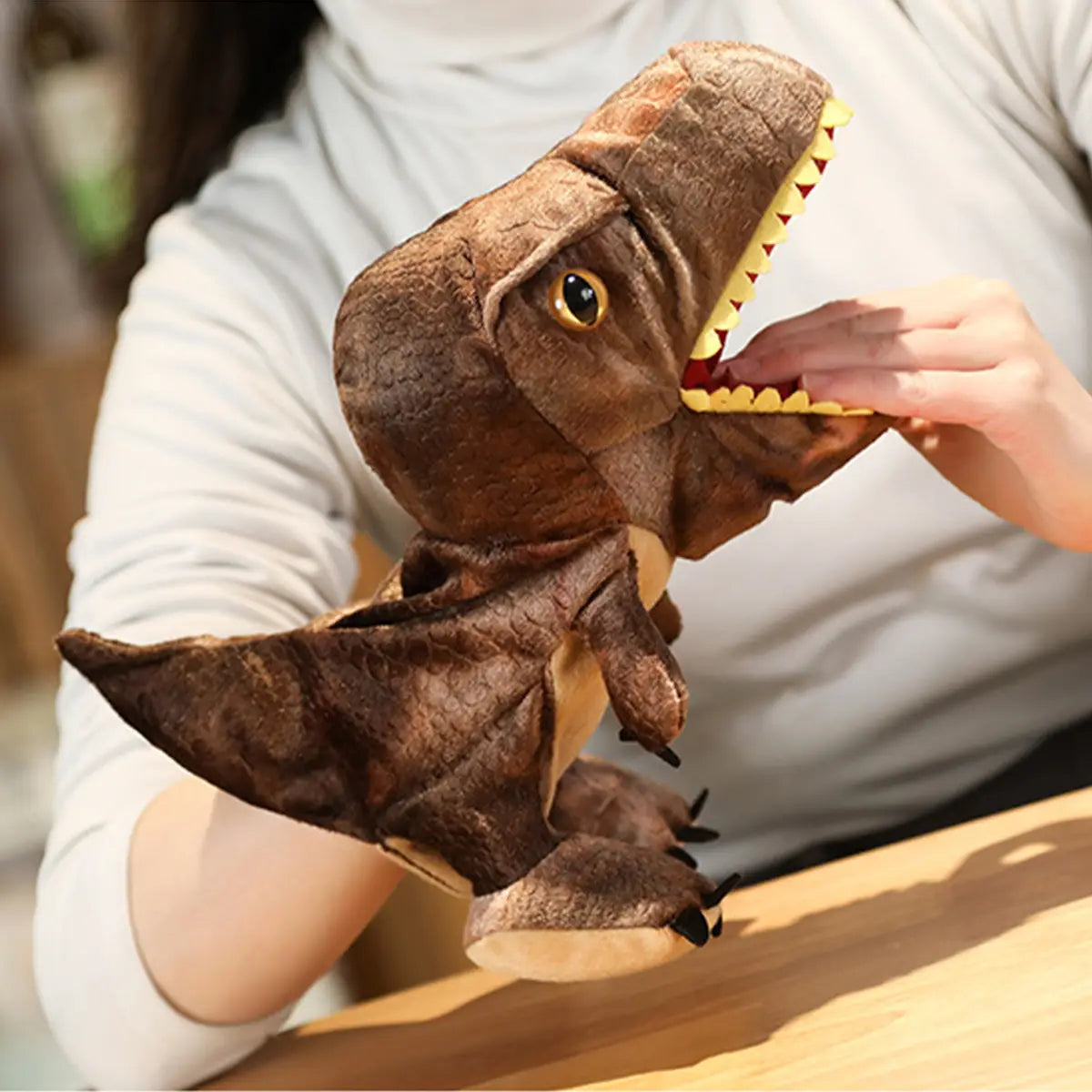 黄色い歯と黒い目を備えた茶色のぬいぐるみティーレックス恐竜の手人形で、想像力を使って遊ぶためのインタラクティブなおもちゃとして設計されている。