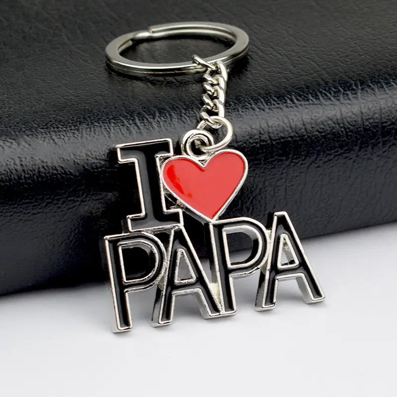 Geschenkset für einen Metall-Schlüsselanhänger im Familienbuchstaben-Look aus silbernem Emaille-Metall mit einem Schlüsselanhänger im „I heart papa“-Design: leuchtend rotes Herz und fette, schwarz umrandete Buchstaben.
