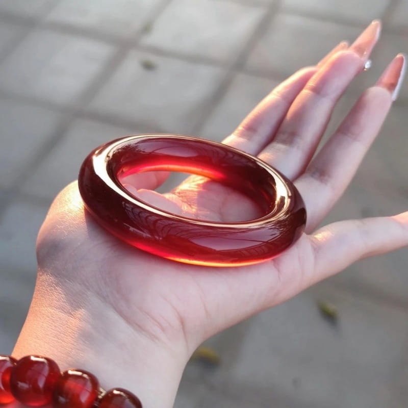 Red jade bangle bracelet for women featuring a translucent deep red color with a smooth polished surface and subtle engraved patterns in a classic round style.
