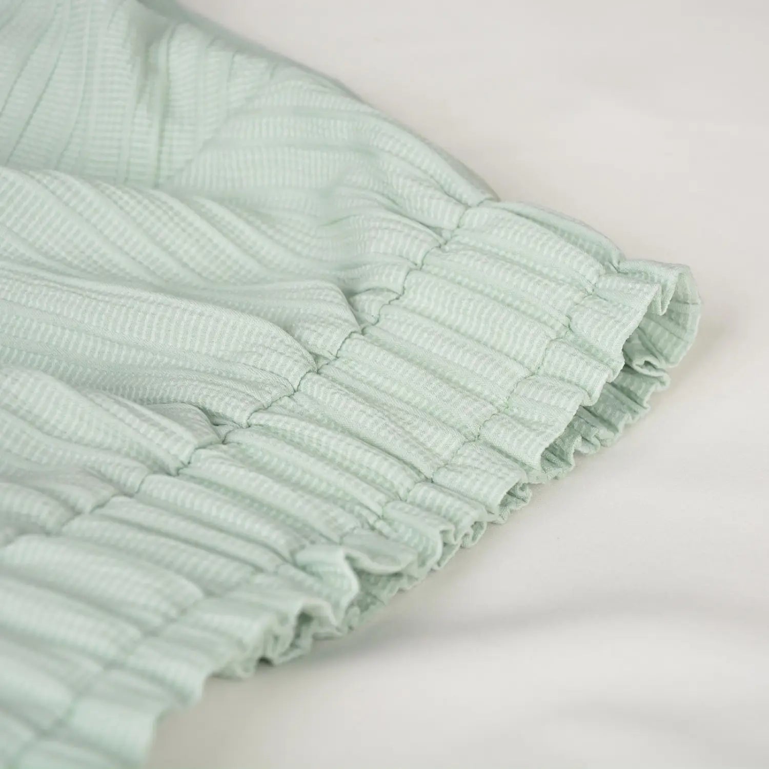 Light green high waist ruffle mini skirt made of softly textured fabric with a gathered ruffled hem.