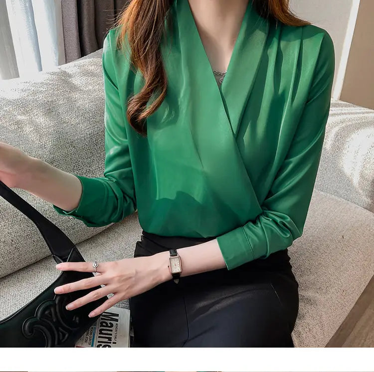 Vネックラインと長袖を備えた、女性向けの洗練されたエメラルドグリーンのサテンブラウス。