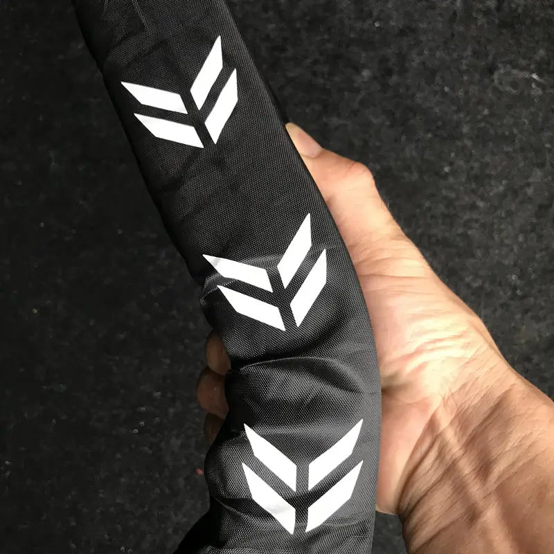Guardacadenas para bicicleta de tela negra con logotipos de punta de flecha blancos, presentado en el organizador flexible del maletero del coche y en la varilla de almacenamiento.