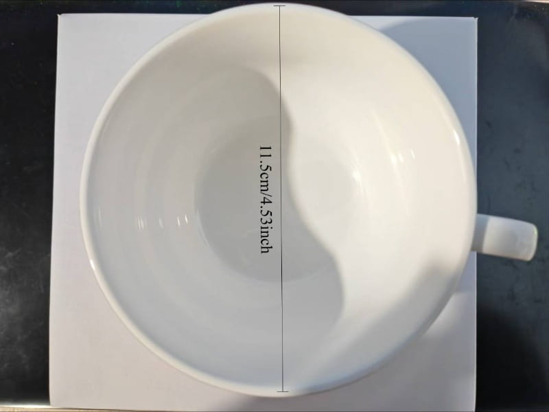 White ceramic coffee cup with a smooth glossy finish and simple curved handle in a ceramic coffee cup and saucer set vintage green rim.