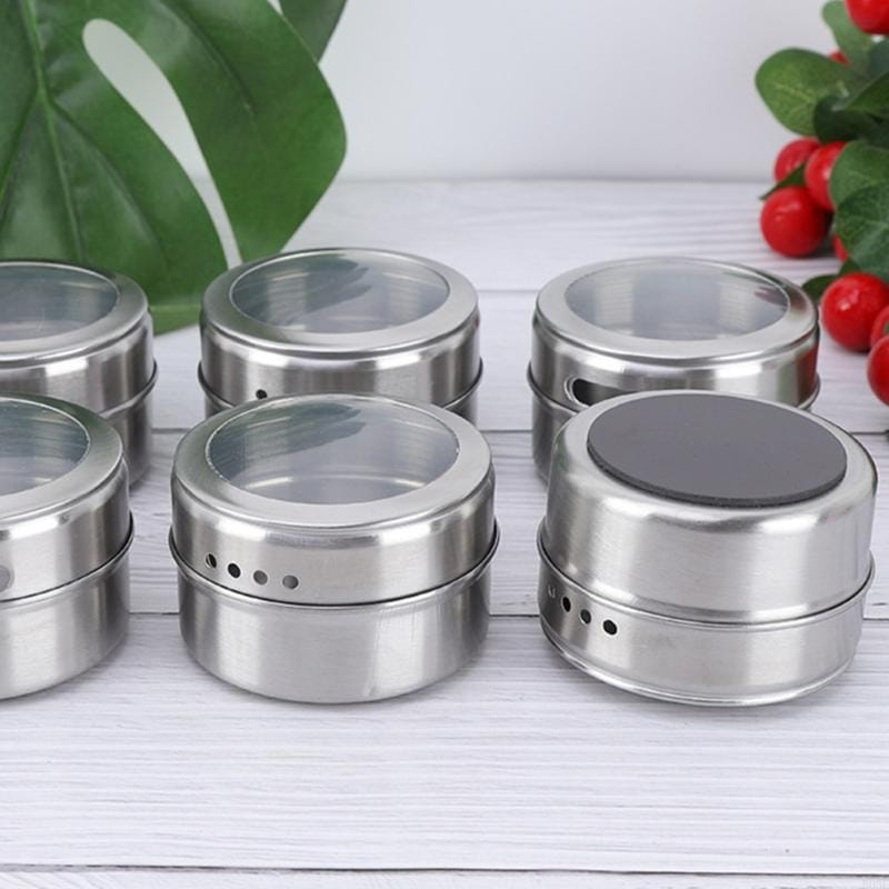 Set mit sechs eleganten Gewürzgläsern aus Edelstahl mit klaren Glasdeckeln und gelochten Seiten zur Belüftung, enthalten in einem Gewürzgläser-Set aus Edelstahl mit Tablett.