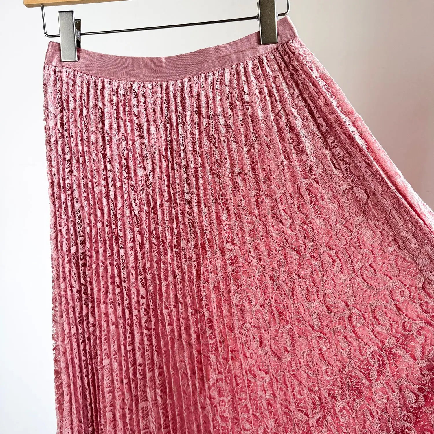 A pink high waist pleated midi skirt made of lace with delicate floral patterns and a soft flowing design suitable for Y2k streetwear.