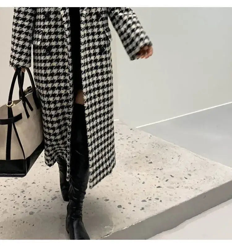 A black and white houndstooth wool double breasted coat with textured fabric.