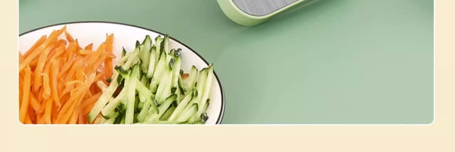 a multi-functional stainless steel vegetable slicer shredder displaying neatly arranged bright orange shredded carrots and crisp green cucumber ribbons on a white plate with a black rim