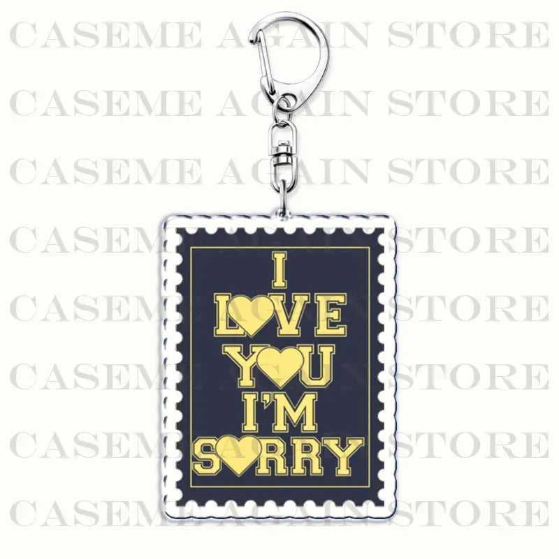 A rectangular Gracie Abrams acrylic keychain with a silver metal clasp featuring a dark blue stamp-style design bordered in white and gold lettering displaying i love you im sorry, ideal as an anime fan gift.