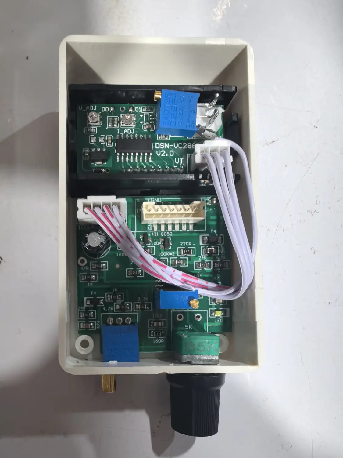 Carte de circuit imprimé verte avec connecteurs bleus et blancs à l’intérieur d’un boîtier en plastique beige d’un régulateur de courant et de tension numérique 50 A, 60 A, 100 A.