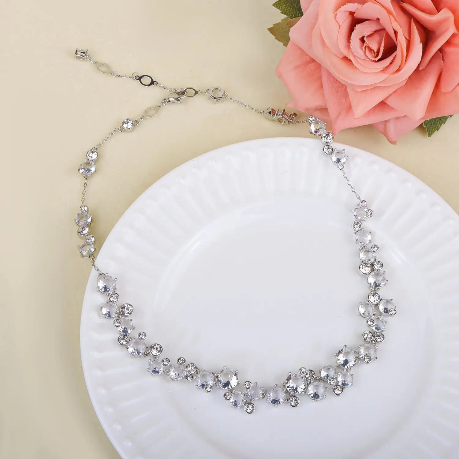 Un ensemble délicat de bijoux de mariage en cristal argenté, comprenant un collier orné de cristaux transparents étincelants et d’un motif de chaîne subtil.