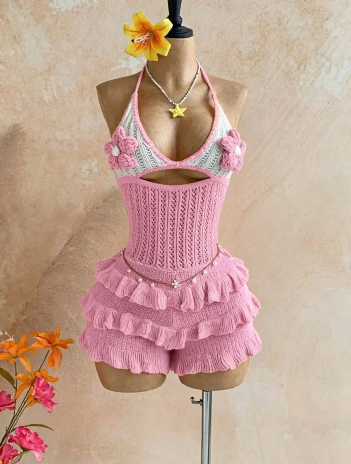 Pink knitted ruffle halter romper summer playsuit with floral embellishments and matching ruffled shorts.