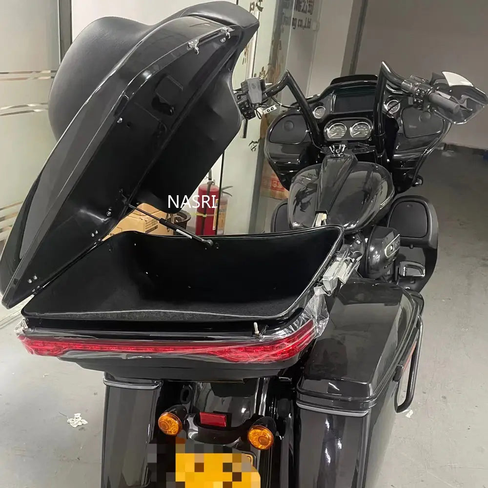 Black glossy hard-shell Harley touring trunk with hinged lid and integrated red taillight shown from the back side for 2014-2023 models.