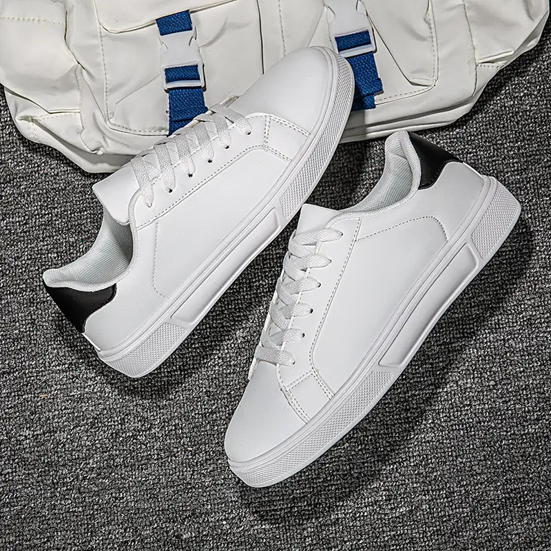 Weiße Ledersneaker im Freizeitstil, leichte Sportschuhe, mit einer glatten lederähnlichen Oberseite, weißen Schnürsenkeln, schwarzen Akzenten am Absatz, und einer strukturierten Gummisohle.