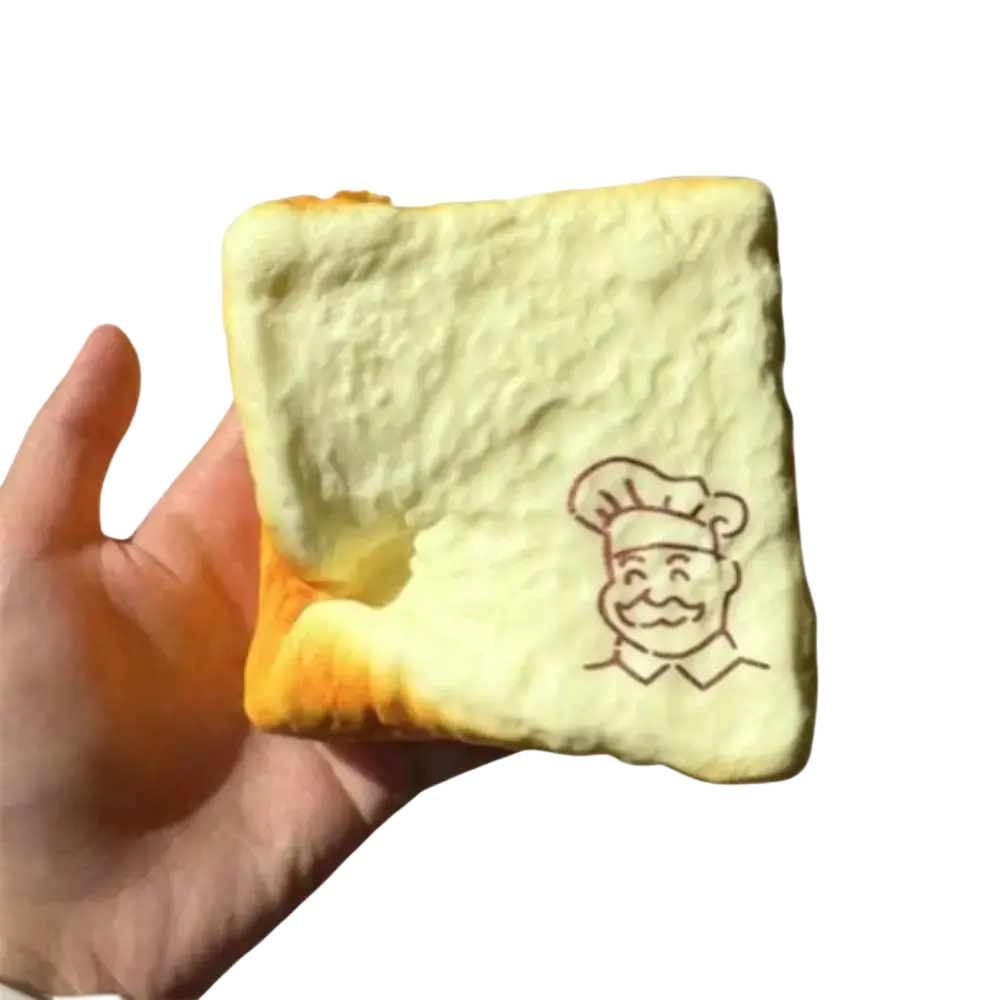 A soft pale yellow foam fidget toy shaped like toasted bread with a smiling chef illustration for universal age range