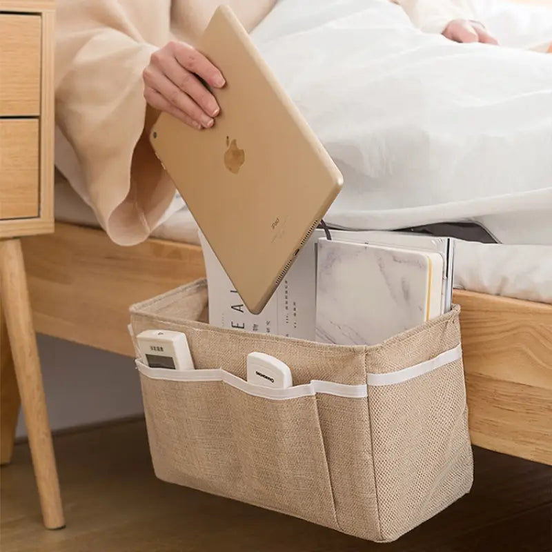 beiges gewebtes Aufbewahrungstaschen-Set für das Schlafzimmerbett mit weißem Abschluss und mehreren Fächern zur Organisation im Kinderzimmer.