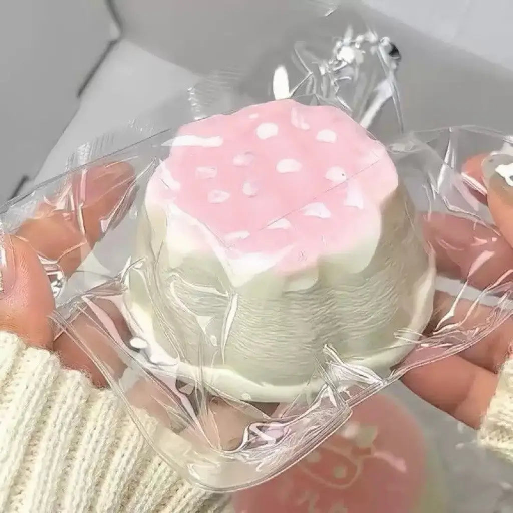Un jouet antistress « squeeze » rose et blanc en forme de fraise, à surface lisse et brillante, conçu comme un article antistress sensoriel de dessert kawaii qui remonte lentement.