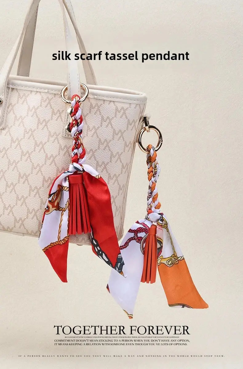 Porte-clés à glands en soie élégants pour sacs, avec des pendants en soie rouge vif et orange, des motifs tressés complexes et un tissu à motifs classiques noué en nœuds décoratifs.