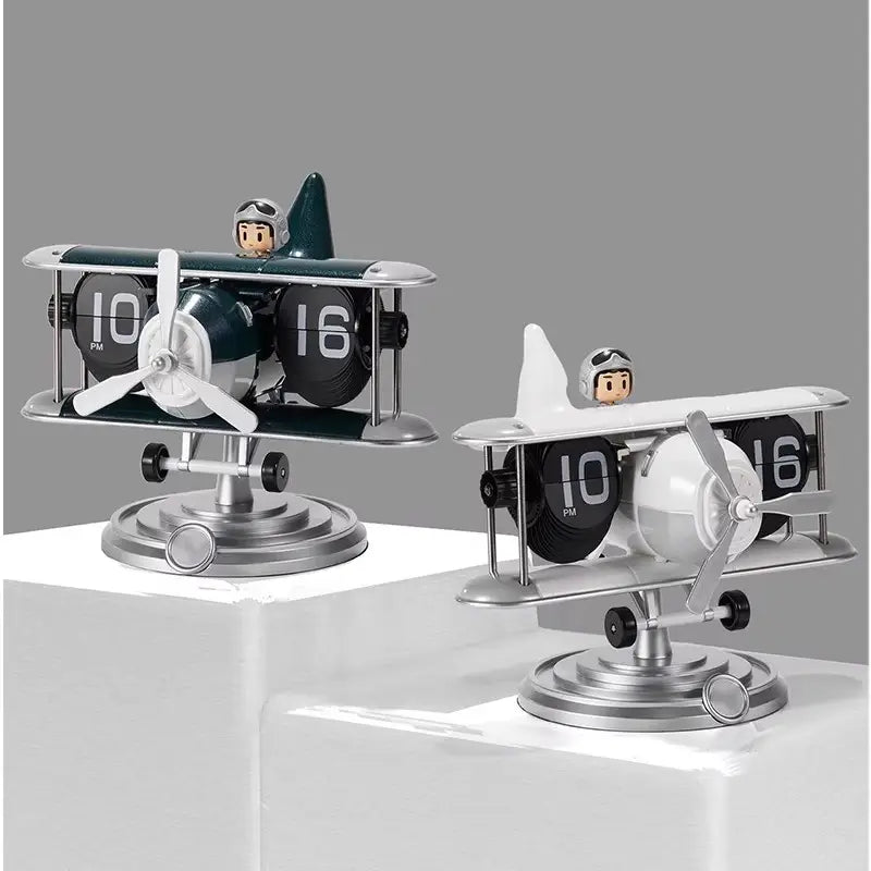 Two vintage-style airplane flip desk clocks in dark green and silver and white and silver colors each featuring a pilot figurine as vintage table decor.