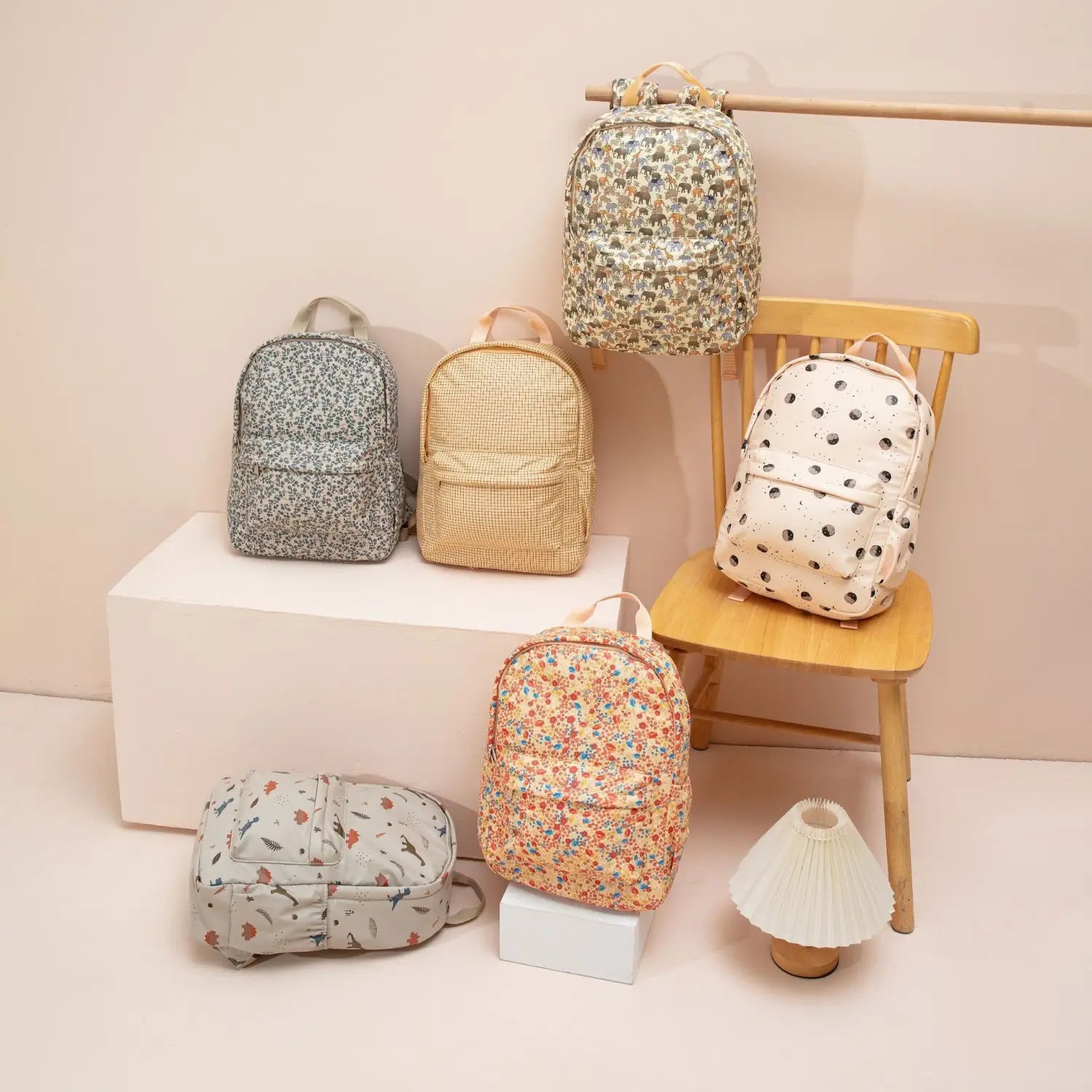 Sac à dos dinosaure pour enfants, style sac d’école pastel, avec un mini sac à dos à motifs floraux dans une teinte pêche douce, orné de délicates fleurs multicolores et de feuilles vertes, confectionné dans un tissu léger.