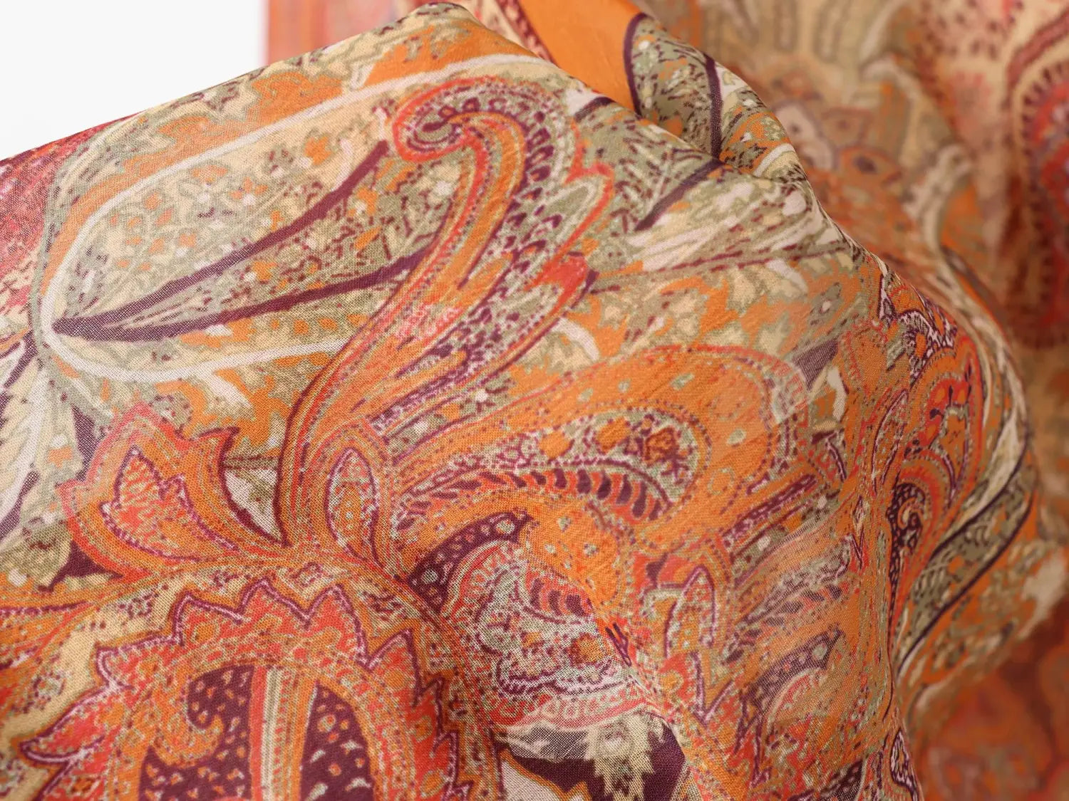Jupe midi à imprimé cachemire taille haute, présentant un tissu orange et bordeaux éclatant, avec des motifs tourbillonnants complexes.
