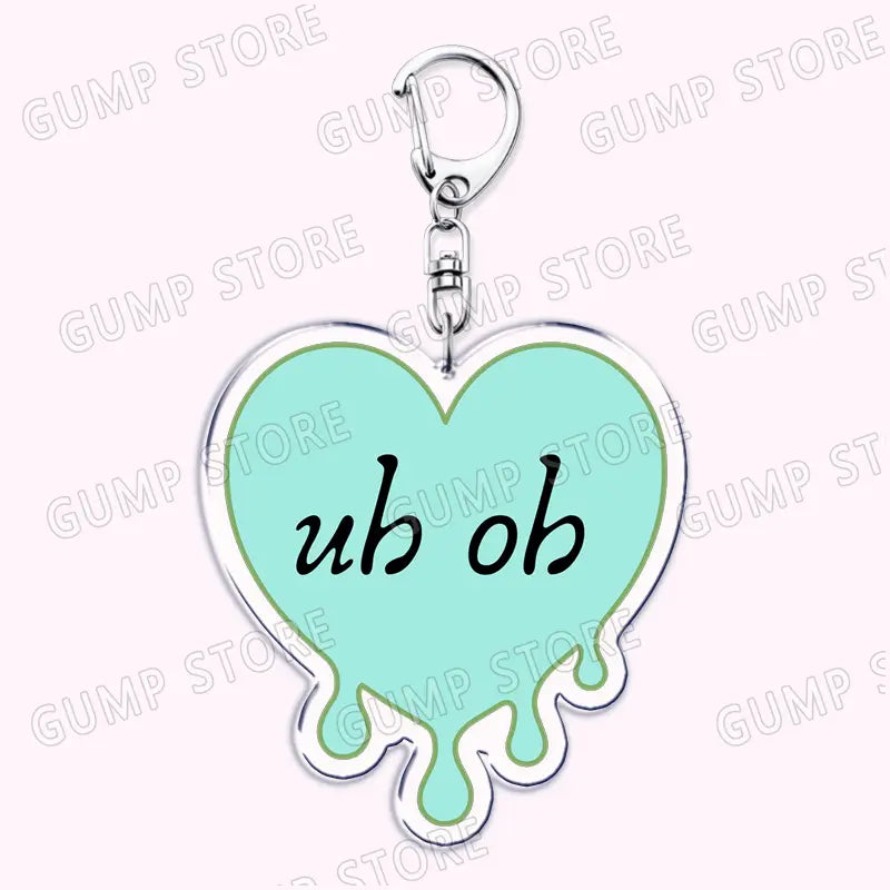 A mint green heart-shaped acrylic keychain with a silver metallic outline and dripping design featuring the text uh oh in black cursive script, part of the Tate Mcrae music fan gift collection.