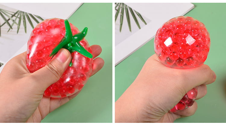 Red tomato-shaped stress relief squeeze ball with green plastic stem and translucent gel beads inside designed for squishy stress relief.