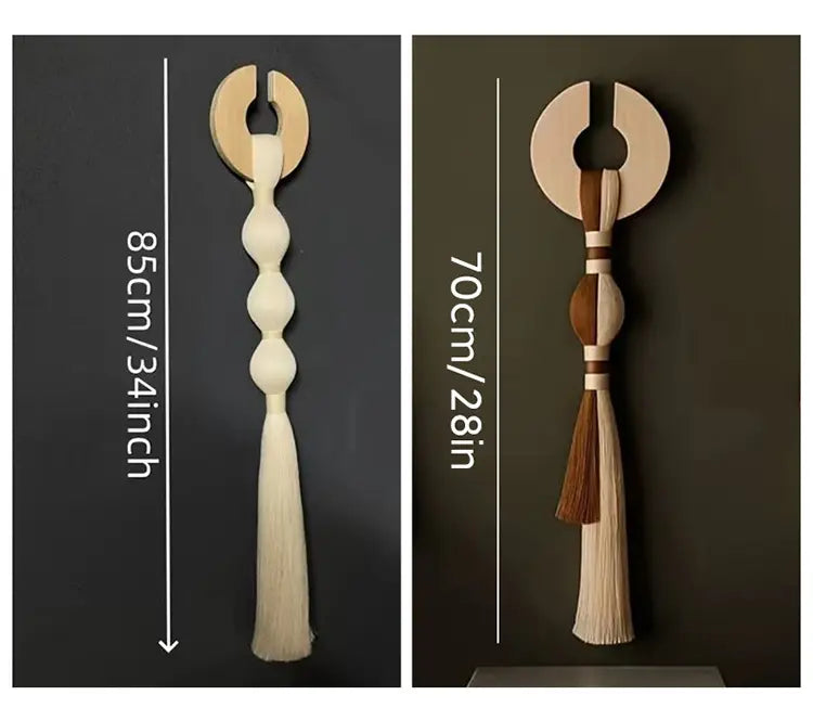 Dos piezas de arte de colgante mural minimalista con borlas tejidas, que presentan una borla de madera retorcida color crema de 85 cm y otra con segmentos alternados de madera clara y oscura y borlas de doble tono de 70 cm.