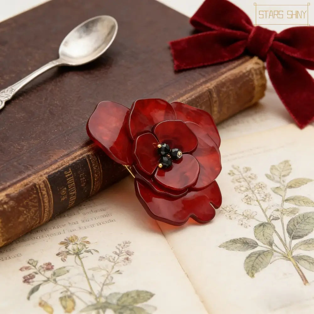 Une broche en émail laqué rouge en forme de fleur de coquelicot, avec un centre noir à perles pour des bijoux de mode.