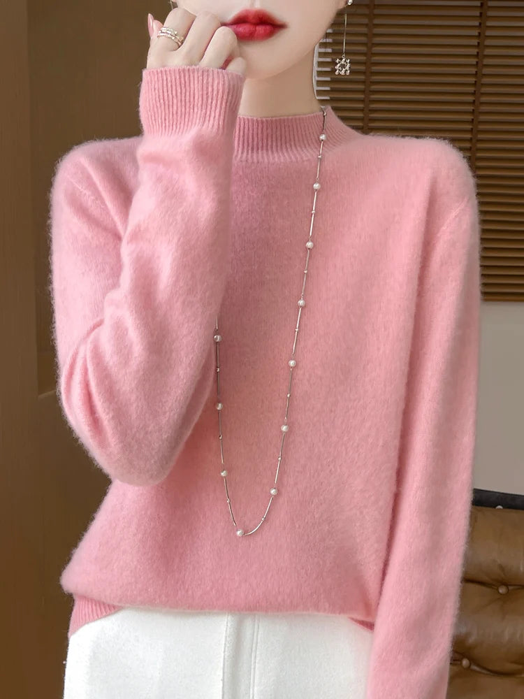 Ein weicher rosafarbener Merino-Wollpullover für Damen mit langen Ärmeln sowie geripptem Ausschnitt und Bündchen.