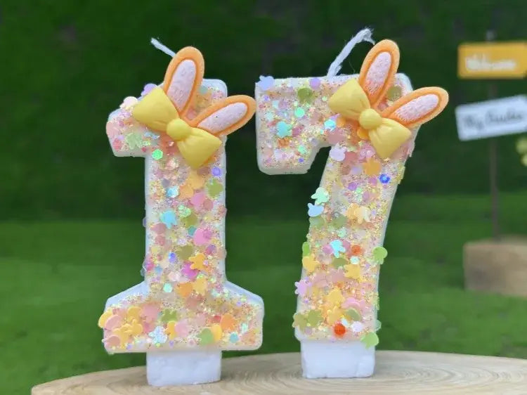 Pastel-colored number 17 birthday candles decorated with glitter, bunny ears, and yellow bows for festive celebrations.