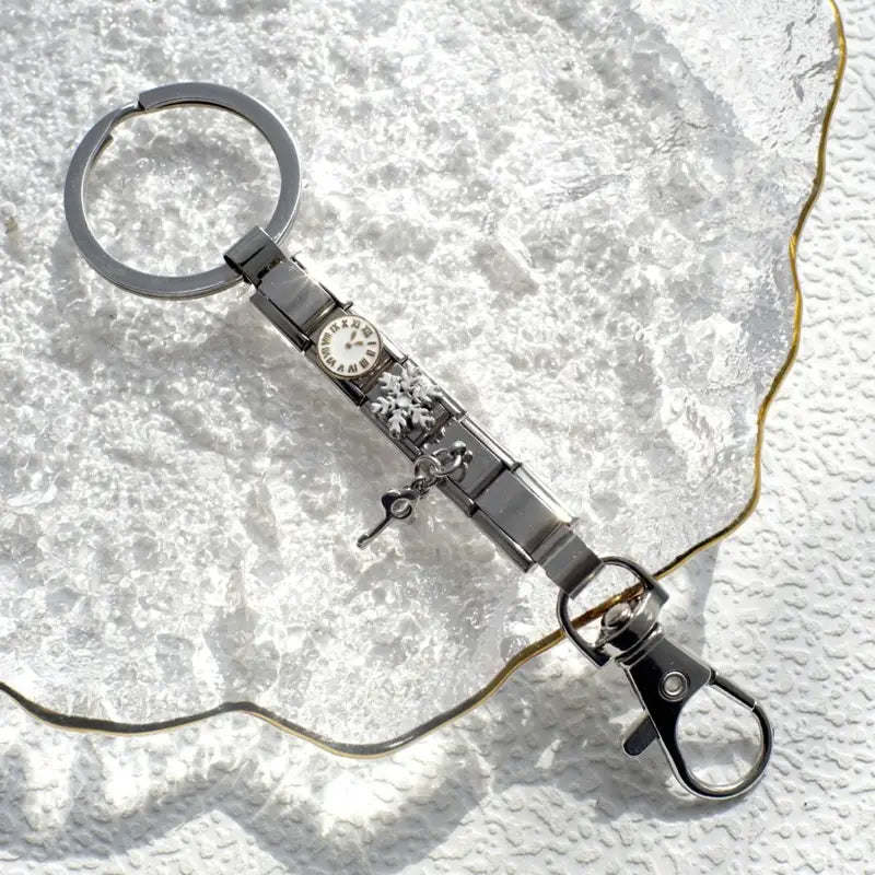 Llavero con dije de eslabones italianos con acabado plateado, con una carátula de reloj en miniatura con números romanos y un intrincado diseño floral, sujeto a un anillo circular y a un broche tipo langosta para uso personalizado en bricolaje.