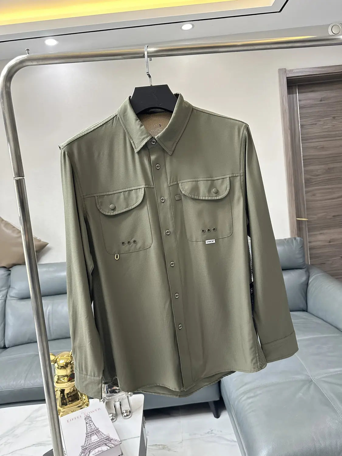 Men’s tactical outdoor long sleeve shirt in olive green leather-like material with button-up front two chest pockets and subtle brand tag.