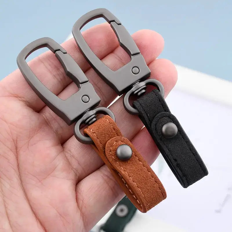 Zwei elegante, matte schwarze Metall-Schlüsselanhänger mit braunen und schwarzen Suede-Riemen, dargestellt im Leder-Schlüsselanhänger-3er-Set als Organizer für Autotasten.