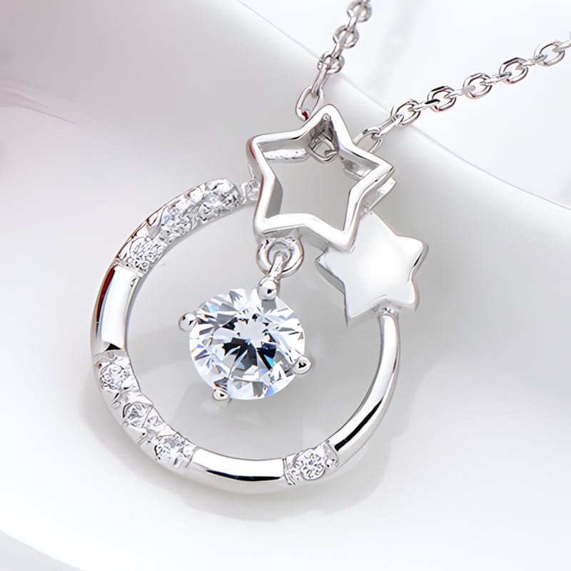 Collier pendentif en zircon plaqué argent sterling pour femmes, présentant un croissant de lune en argent avec un cristal transparent central, des pierres scintillantes le long de sa courbe, ainsi que deux breloques en forme d’étoile pendantes.