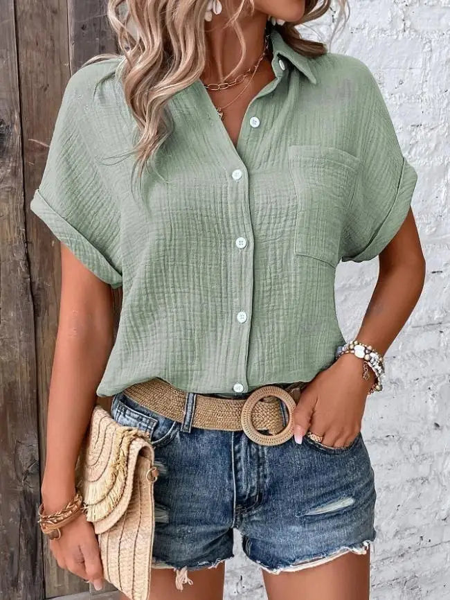 A light green women cotton short sleeve button up shirt with subtle textured fabric and rolled cuffs.