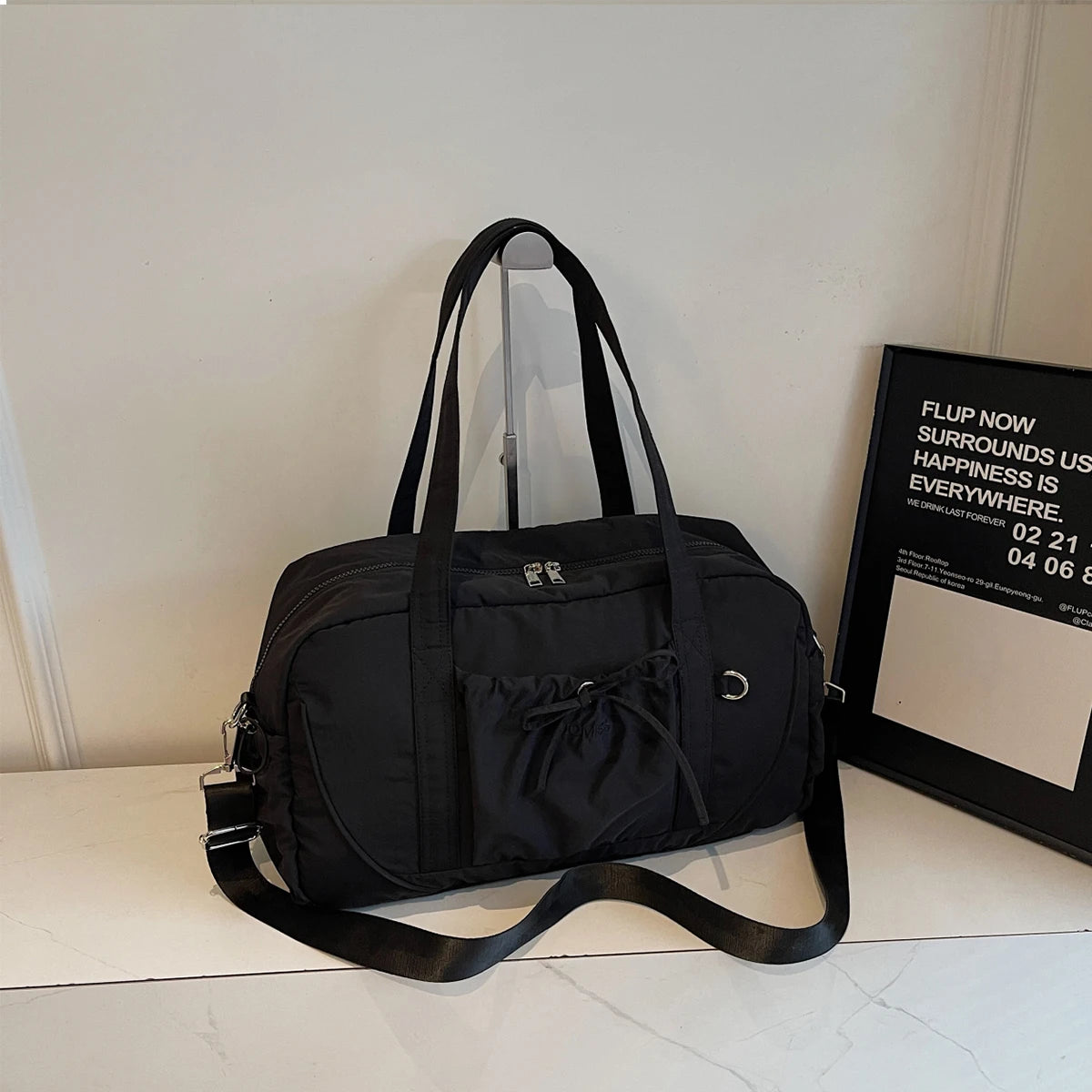 Black nylon travel duffel bag with large capacity featuring dual top handles and a detachable shoulder strap for women handbag use.